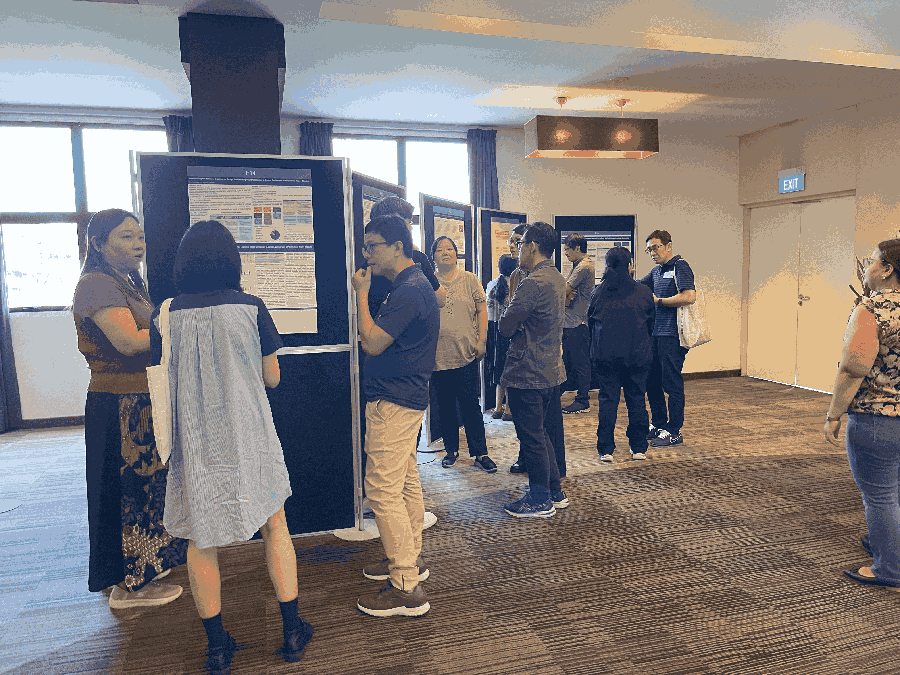 Participants at a poster presentation session engaging in discussions in a carpeted hall.