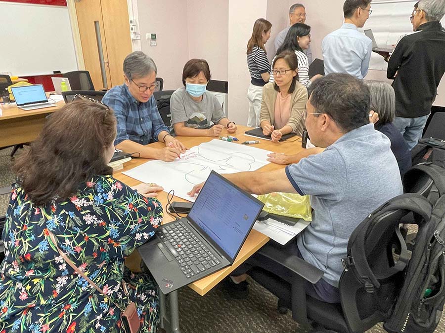 Gemini said A small group of participants collaborating on a large paper sketch during a workshop.